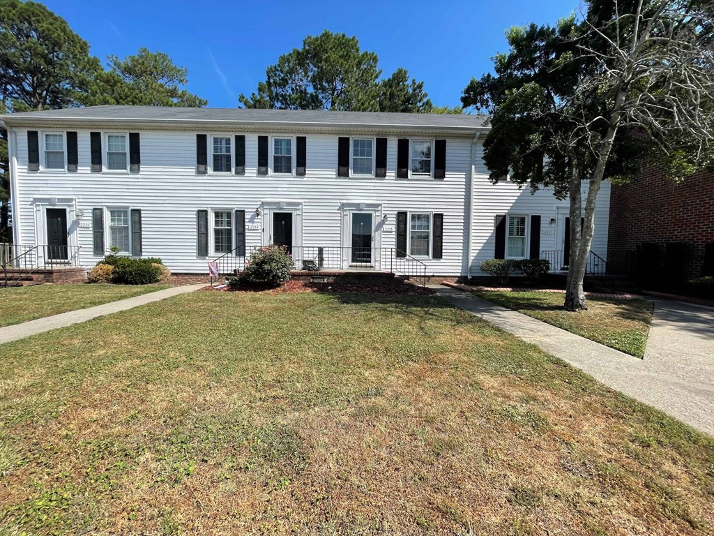a white house with a lawn and trees in front of it