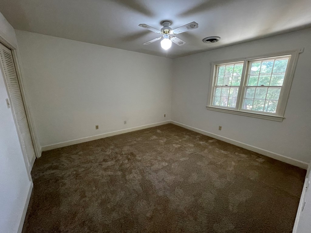a empty bedroom with a ceiling fan and a window