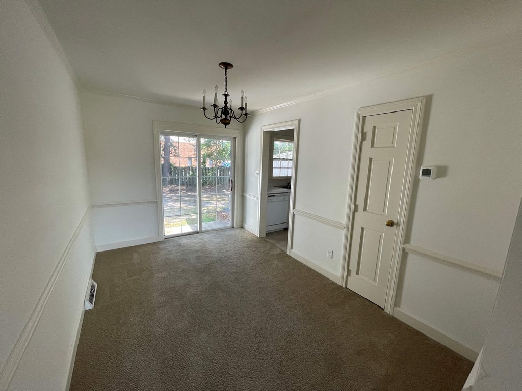 a large empty room with a door and a chandelier