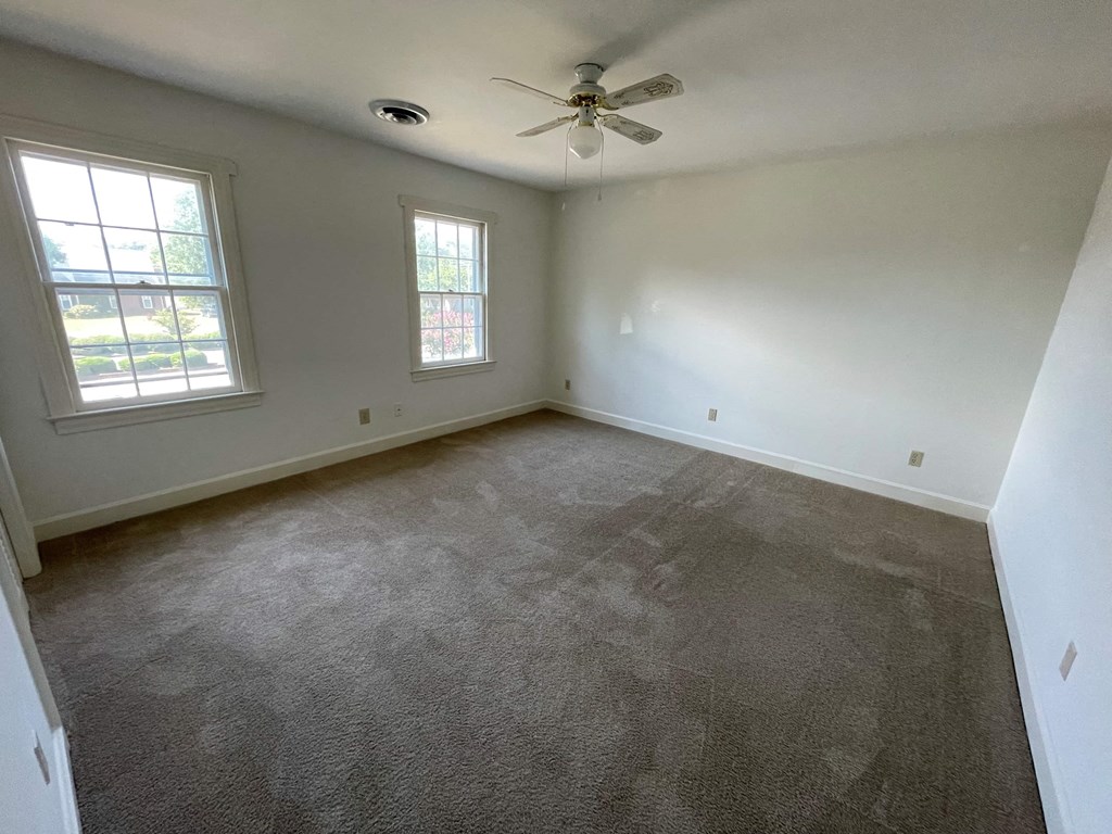a living room with carpet and a ceiling fan