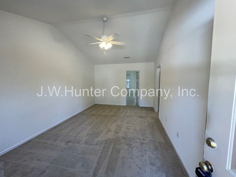 A spacious room with a carpeted floor and a ceiling fan.