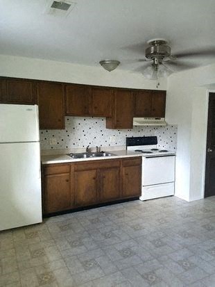 a kitchen with a white refrigerator and stove and a ceiling fan