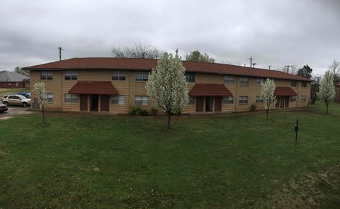 the front of an apartment building with green grass and trees