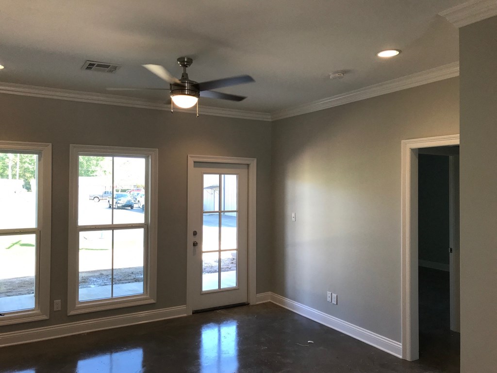 a living room with a ceiling fan and three windows