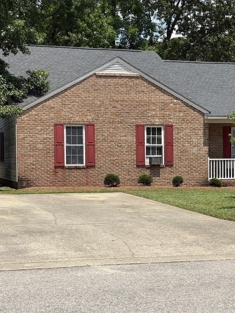 A brick house with a grey roof and red shutters.