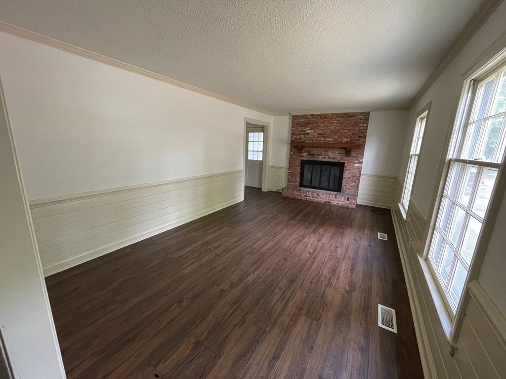 an empty living room with wooden floors and a brick fireplace
