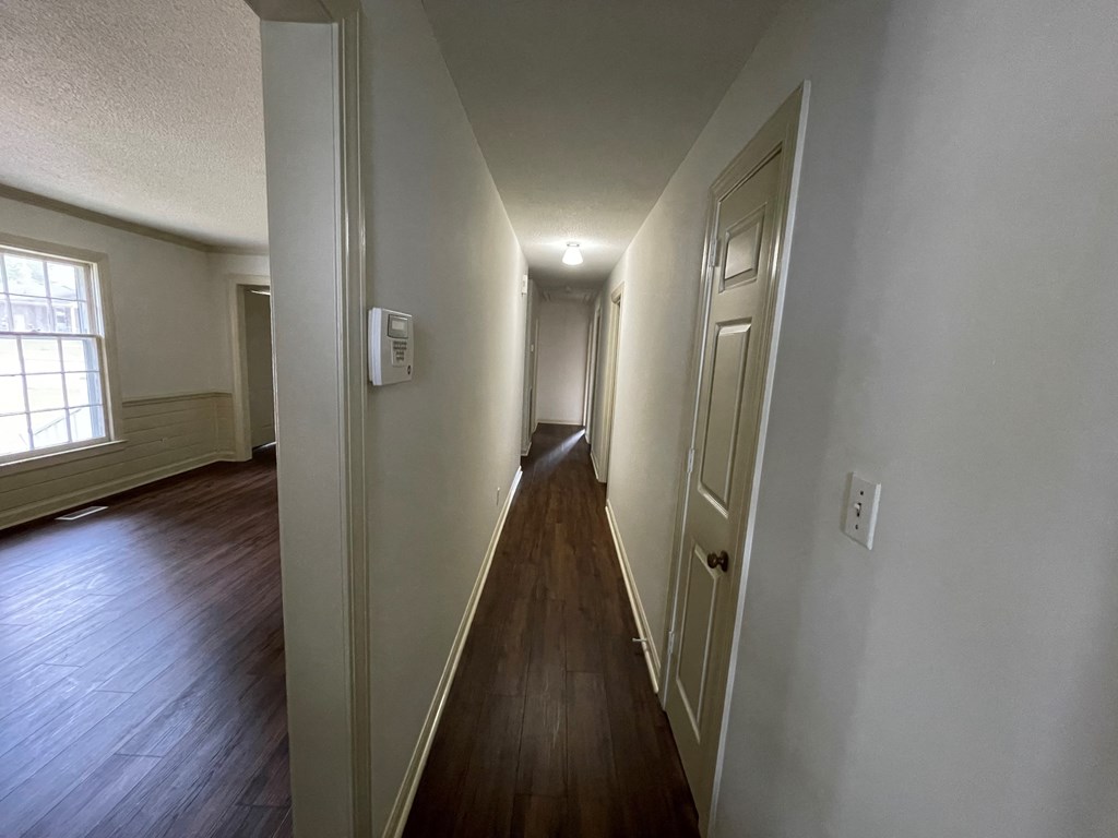 a hallway with wood floors and white walls and a door