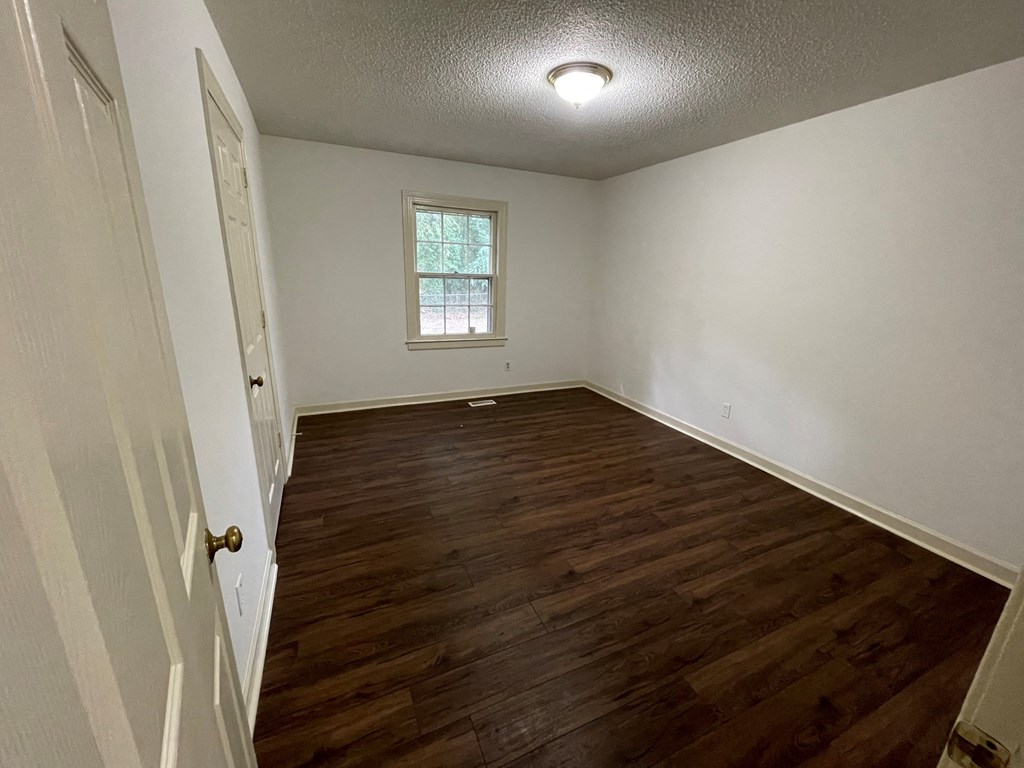 an empty living room with wood flooring and a window