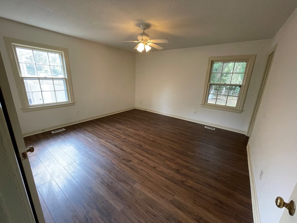 an empty living room with wood floors and a ceiling fan