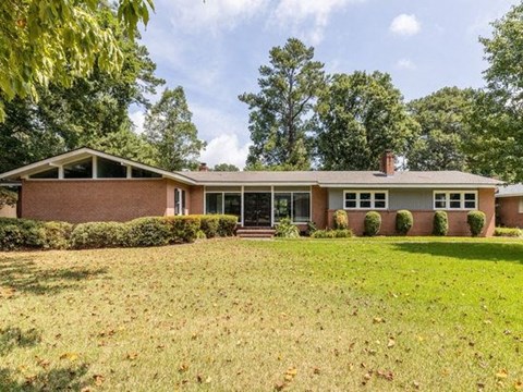 a brick house with a grass yard and trees