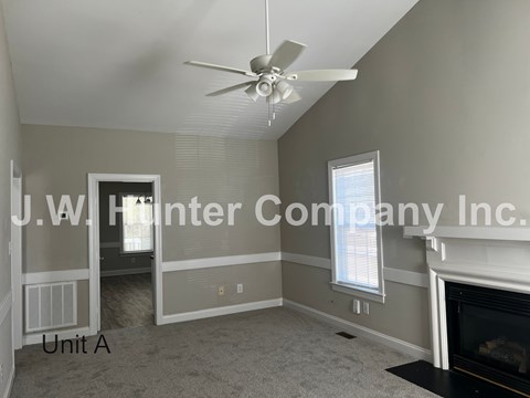 A living room with a fireplace and a ceiling fan.