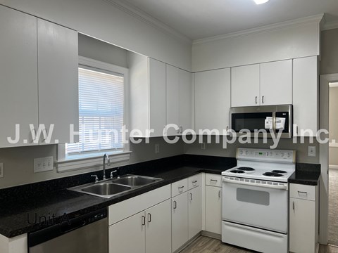 A kitchen with white cabinets and black countertops.