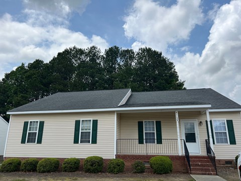 A house with a white siding and green shutters.