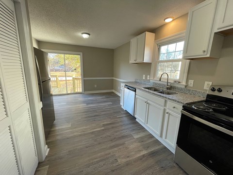 A kitchen with white cabinets and a black stove top oven.