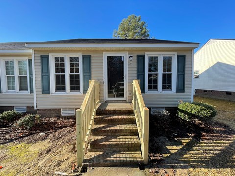 A small house with a wooden staircase leading to the front door.