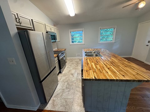 A kitchen with a wooden counter top and stainless steel appliances.