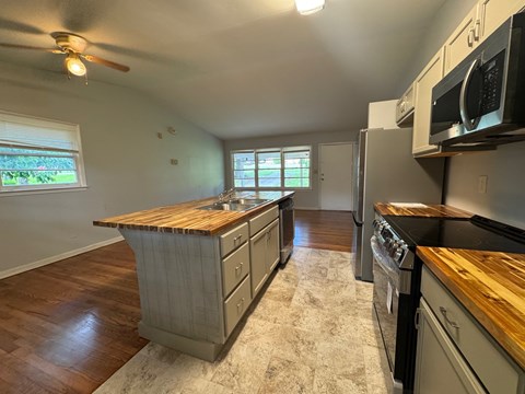 A kitchen with wooden countertops and black appliances.