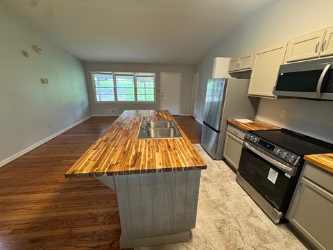 A kitchen with a wooden island and stainless steel appliances.