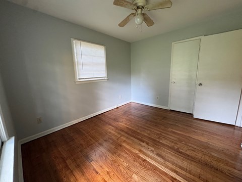 A room with a ceiling fan and wooden flooring.