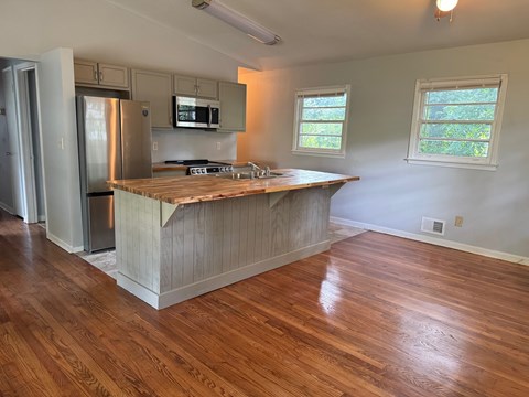 A kitchen with wooden floors and a wooden island.