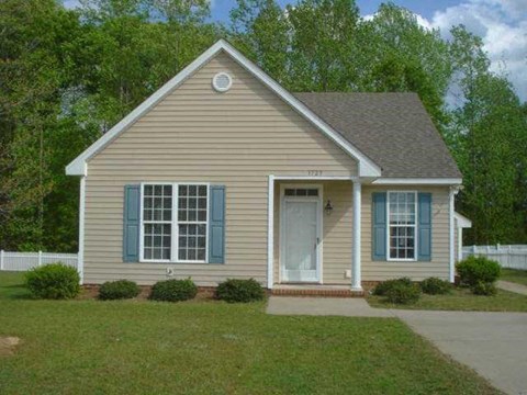 a tan house with blue shutters and a lawn