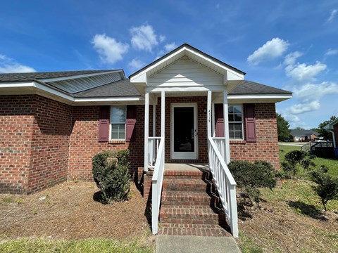 A brick house with a white porch and a black door.