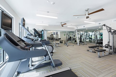a gym with cardio equipment and televisions in a building