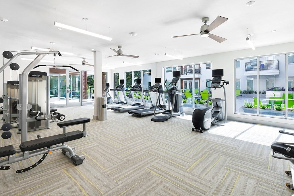 a gym with cardio equipment and windows in a building