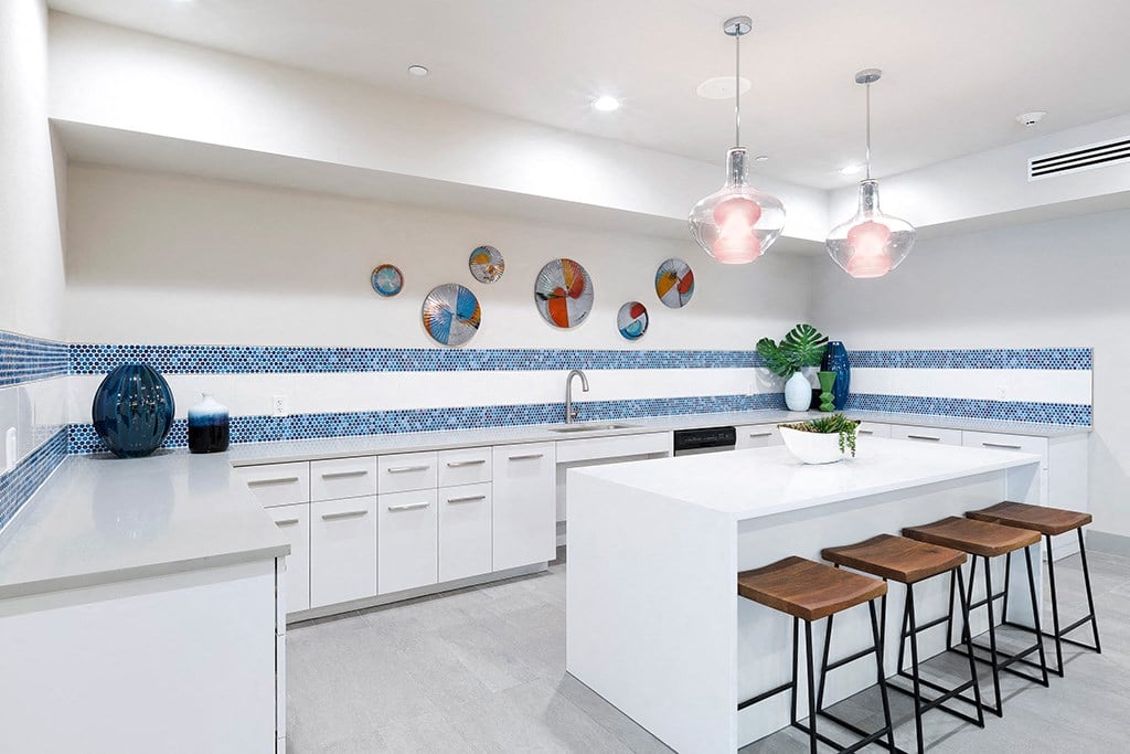a large kitchen with white counter tops and blue and white tiles