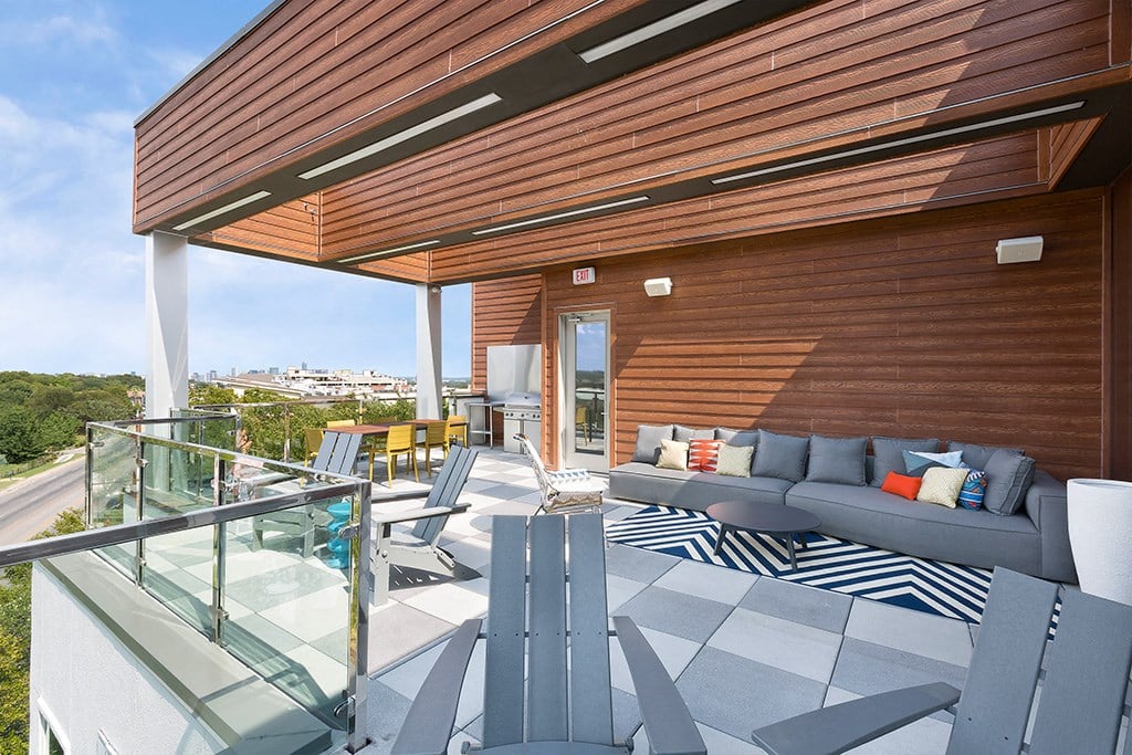 a terrace with couches and chairs and a glass railing