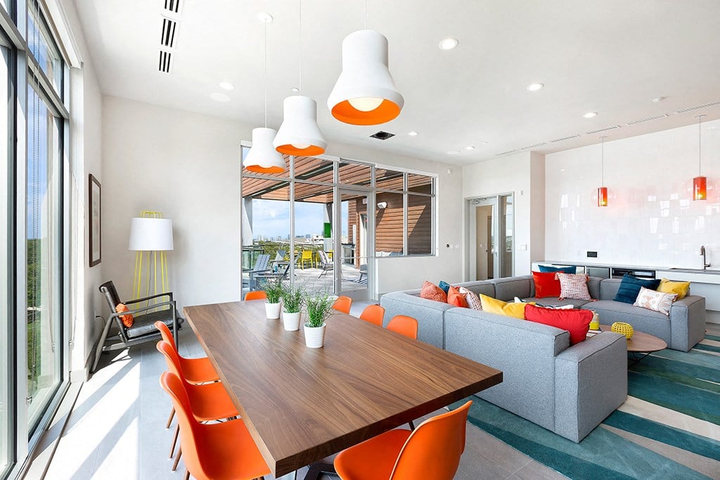 a living room and dining room with orange chairs and a wooden table