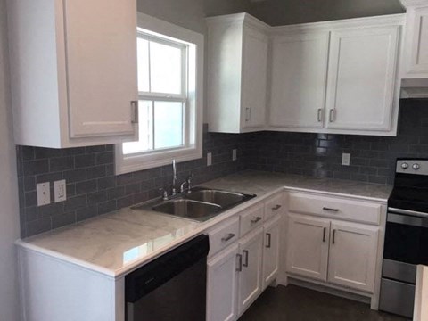 A kitchen with white cabinets and a black dishwasher.