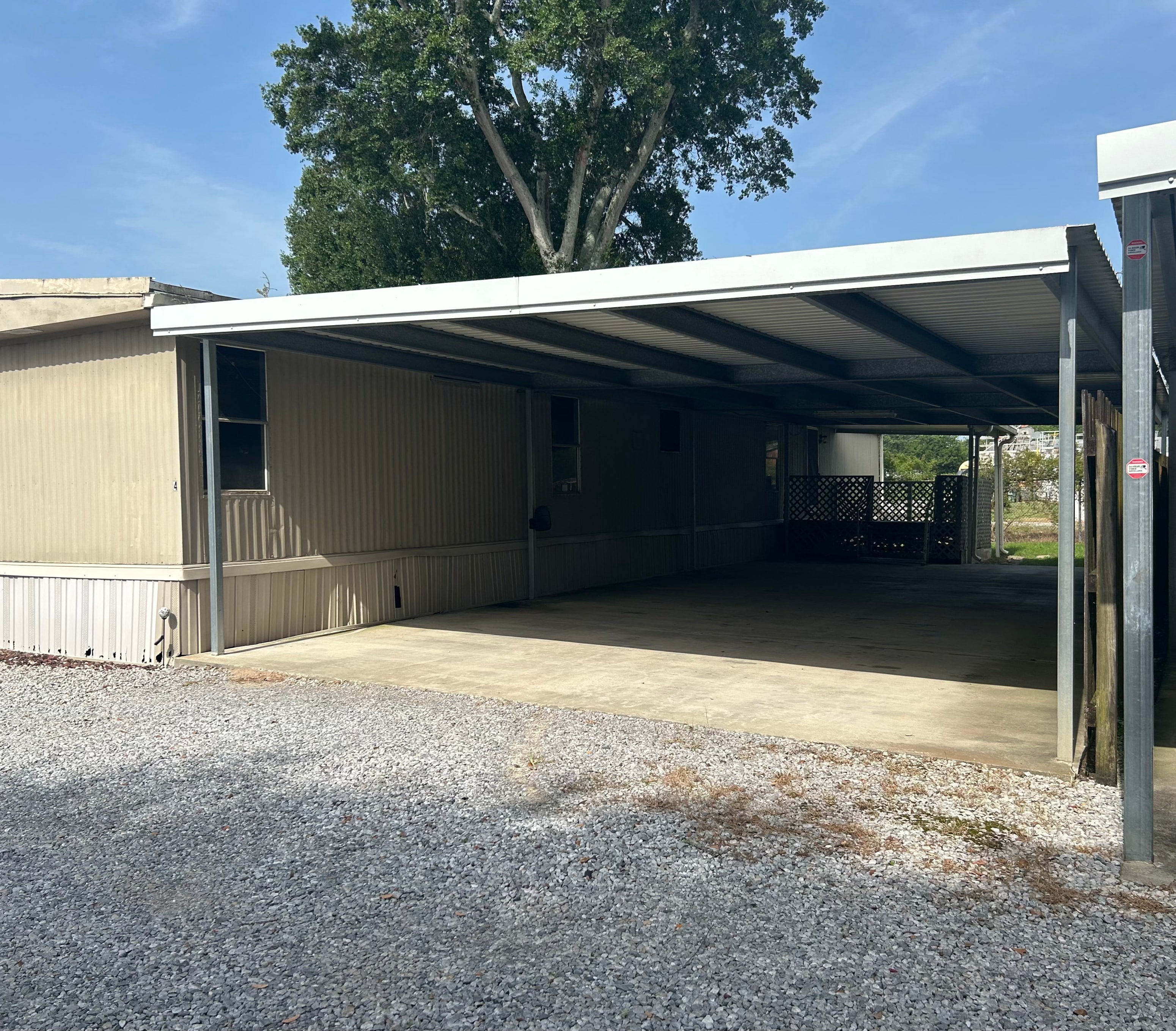A large garage with a metal roof and a gravel driveway.