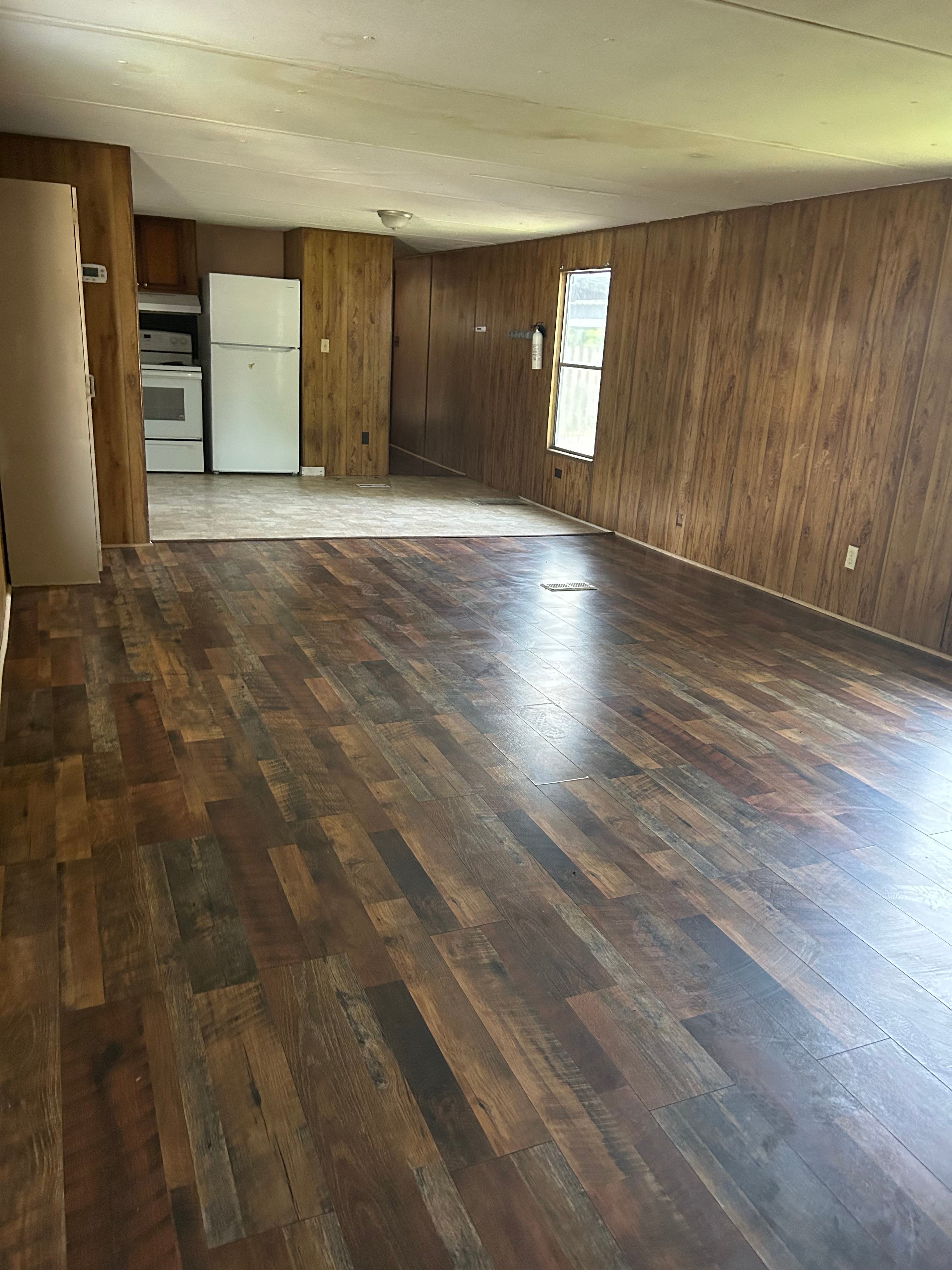 A room with wooden flooring and a white refrigerator.