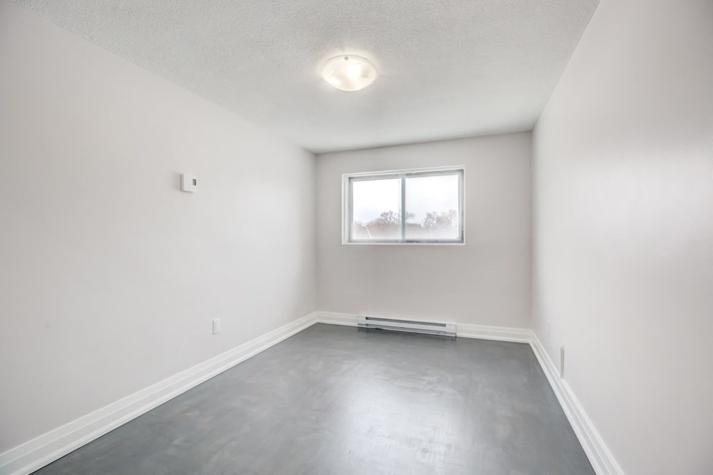 an empty room with white walls and a window
