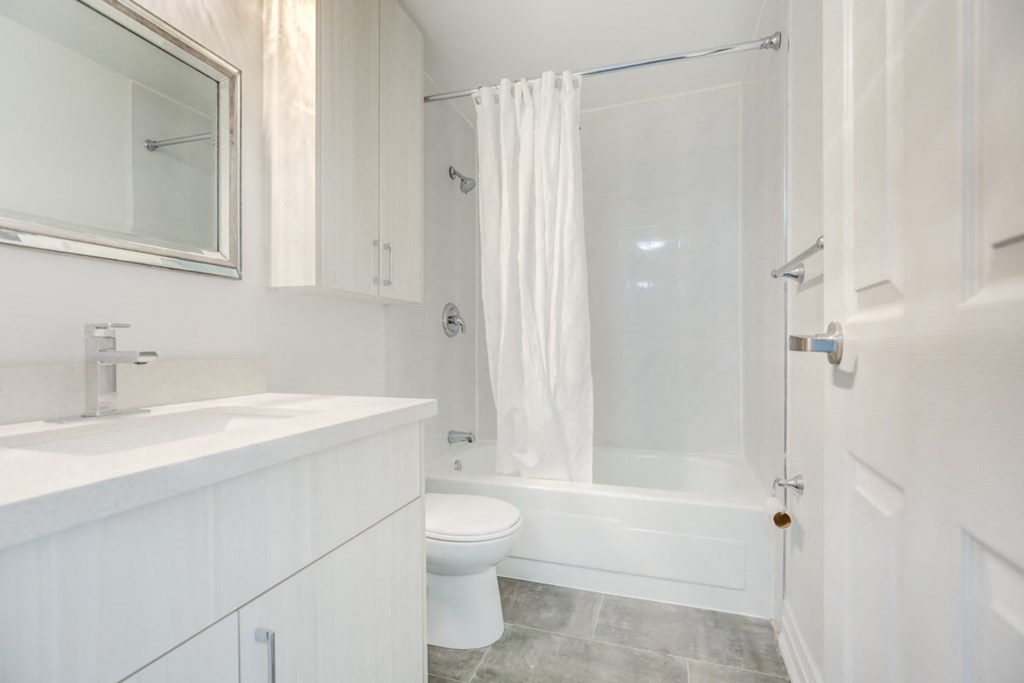 a white bathroom with a shower toilet and sink