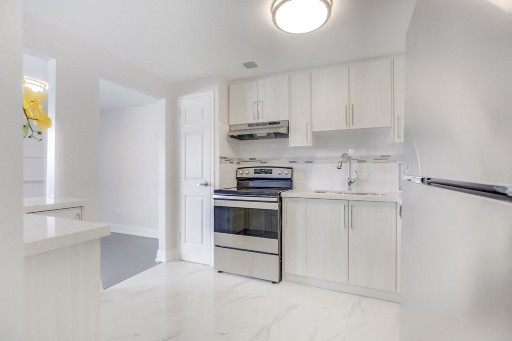 a white kitchen with white cabinets and a stainless steel stove