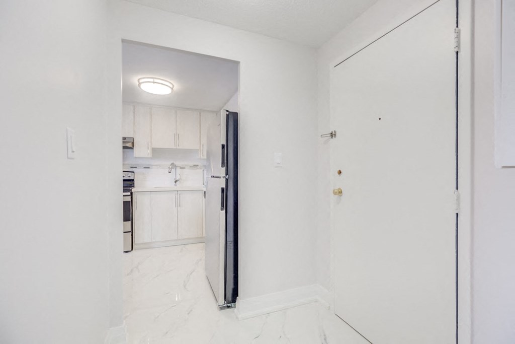 an empty kitchen with a refrigerator and a door