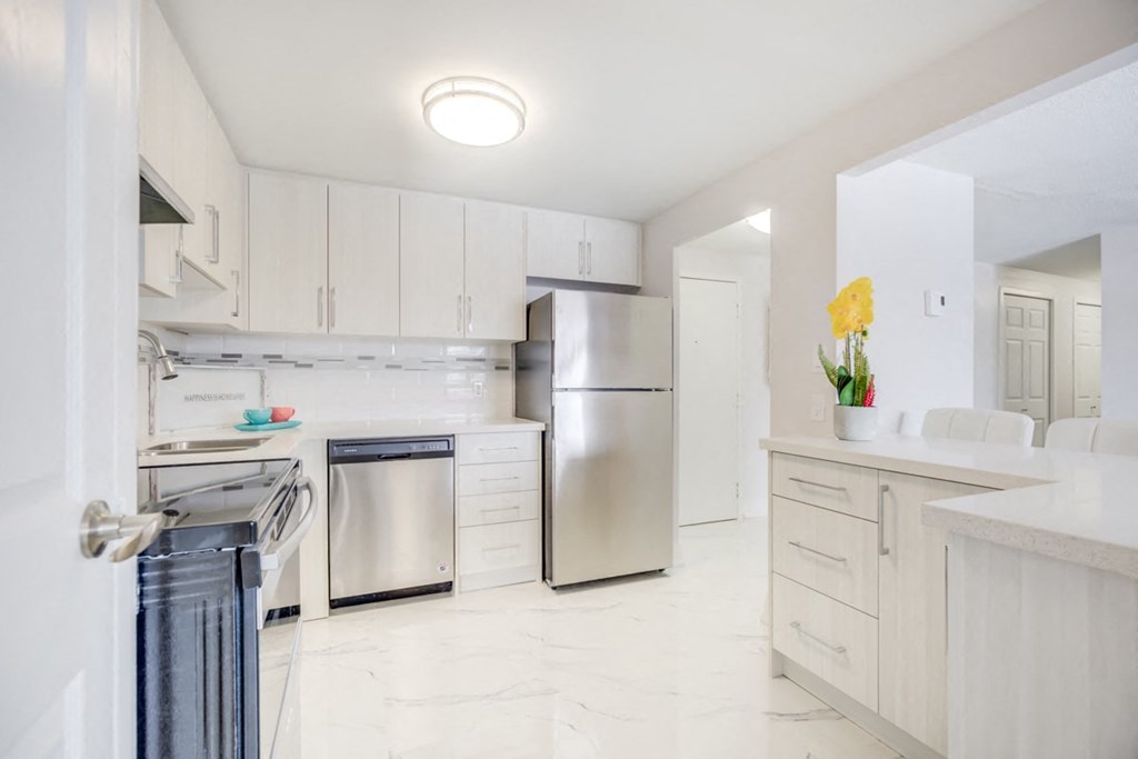 a white kitchen with stainless steel appliances and white cabinets