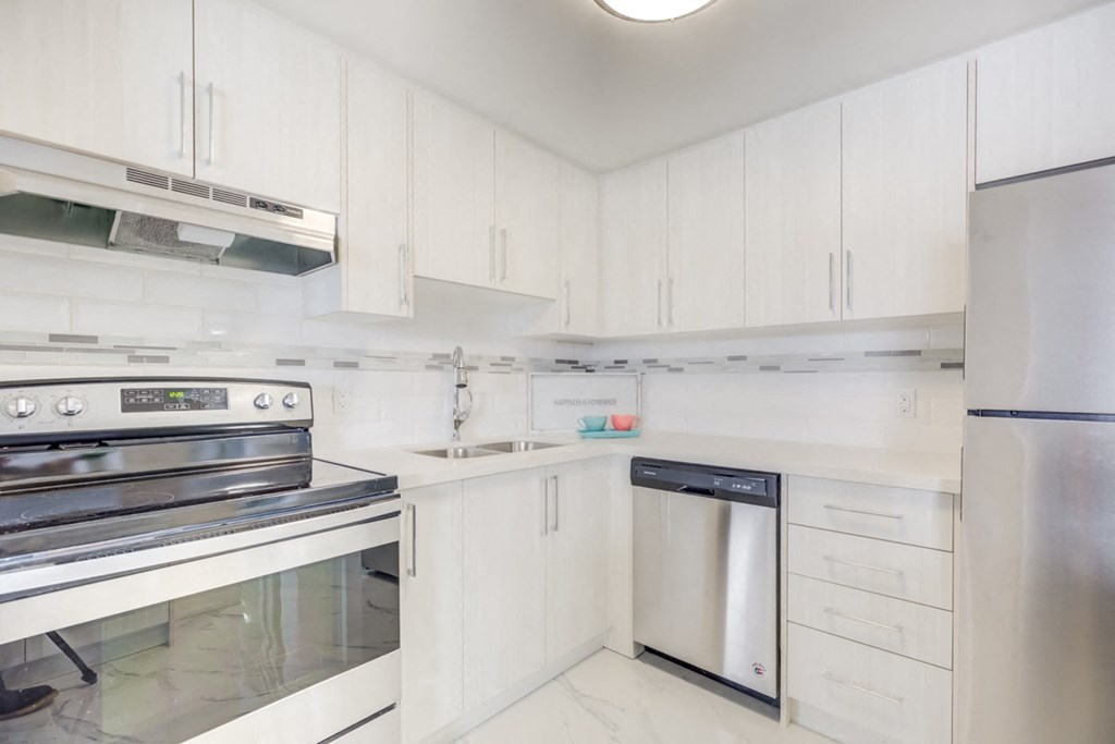 a white kitchen with stainless steel appliances and white cabinets