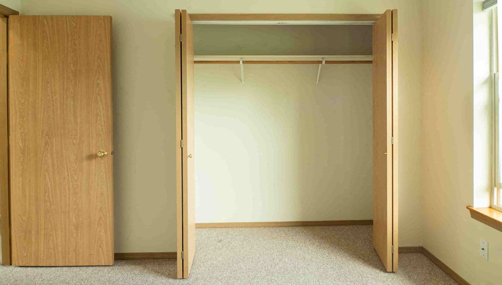 an open wardrobe in a room with a carpeted floor