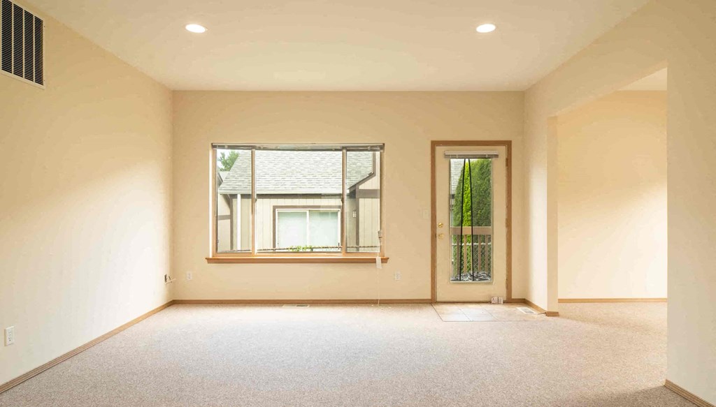 an empty living room with a window and a door