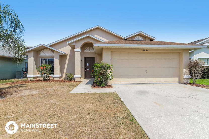 a beige house with a driveway and a garage door