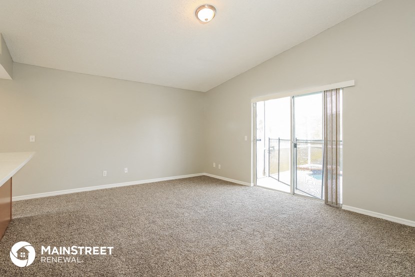 a spacious living room with a balcony and carpeted flooring