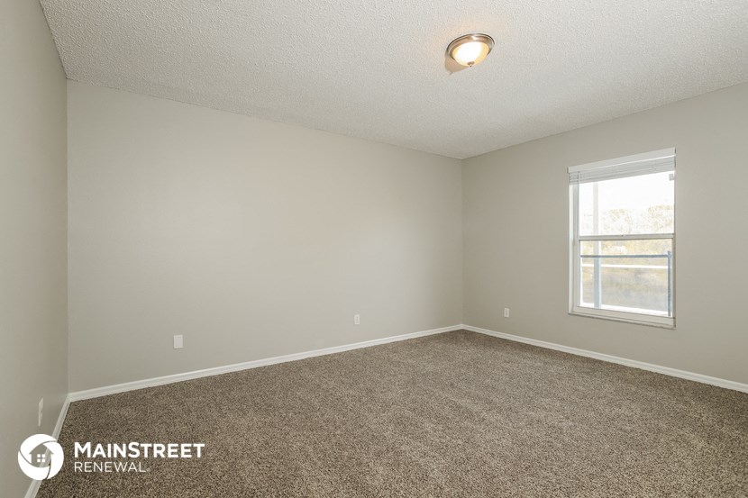 the spacious living room with carpeting and a window