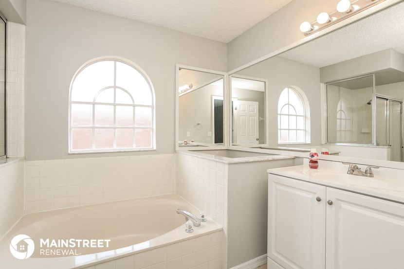 a bathroom with a tub and a sink and a mirror