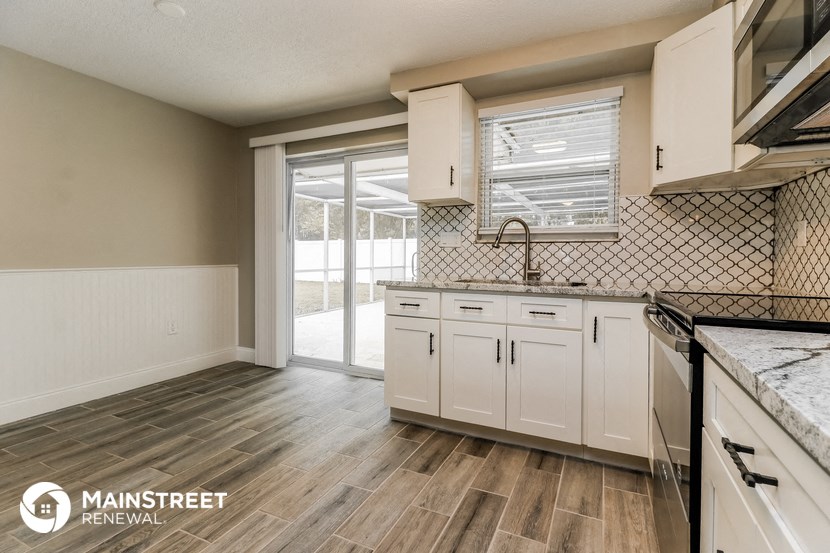 an empty kitchen with white cabinets and a window
