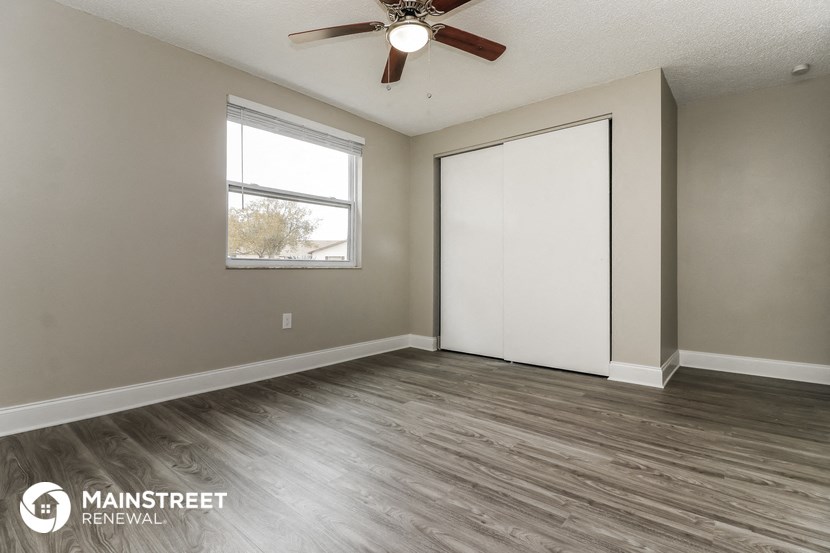 an empty living room with a ceiling fan and a window