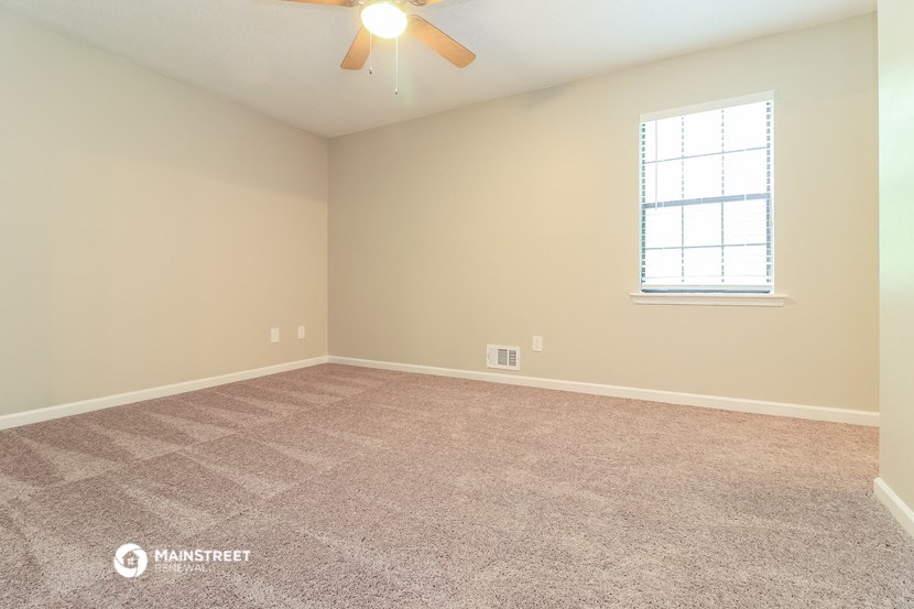 the spacious living room with carpeting and a ceiling fan