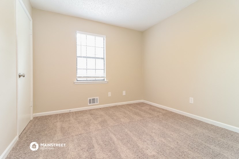 the spacious living room with carpeting and a window